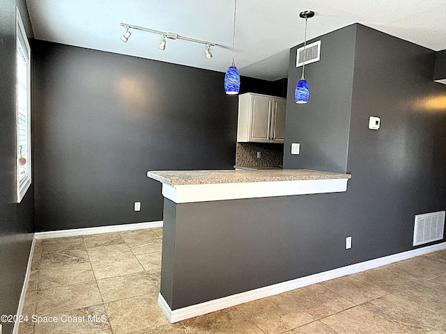 kitchen with white cabinets, kitchen peninsula, hanging light fixtures, and tasteful backsplash