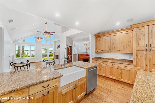 kitchen featuring light stone countertops, light wood-type flooring, ceiling fan, sink, and dishwasher