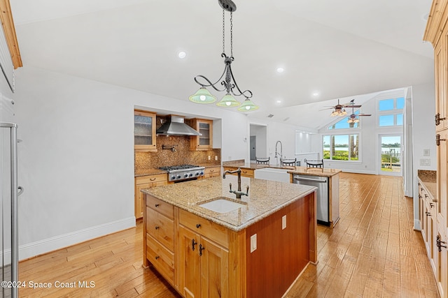 kitchen with appliances with stainless steel finishes, light wood-type flooring, vaulted ceiling, sink, and an island with sink