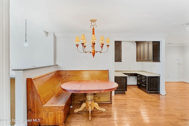 dining space featuring breakfast area, light wood-type flooring, ornamental molding, and a chandelier