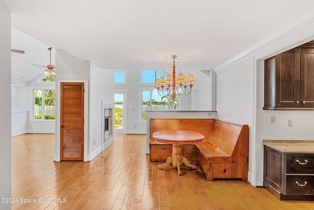 dining area with ceiling fan with notable chandelier, light hardwood / wood-style floors, lofted ceiling, and crown molding