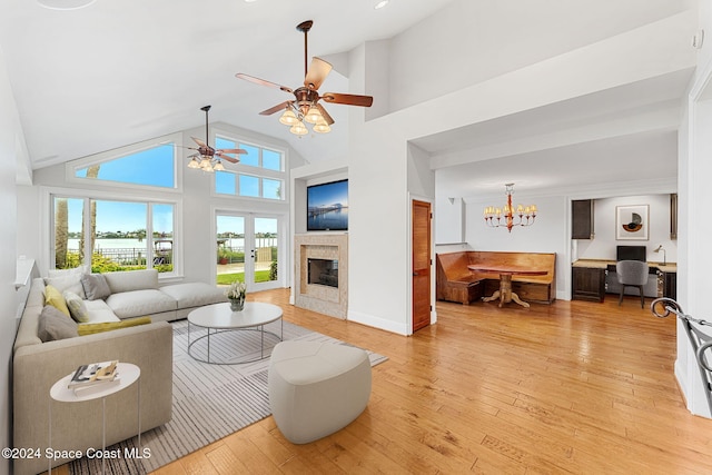 living room featuring french doors, ceiling fan with notable chandelier, light hardwood / wood-style floors, and high vaulted ceiling