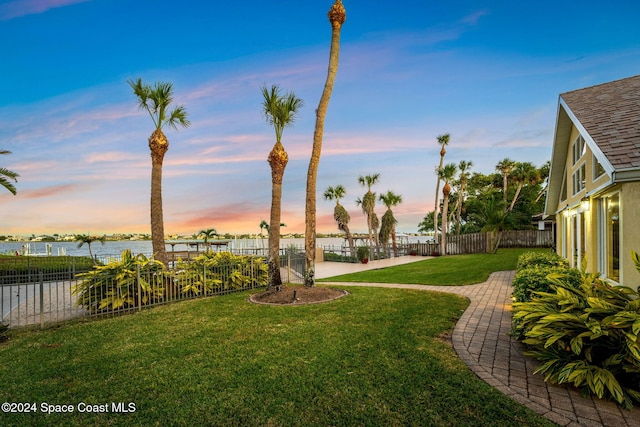 yard at dusk featuring a water view