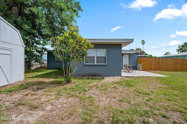 back of house with a storage unit, a patio area, and a yard