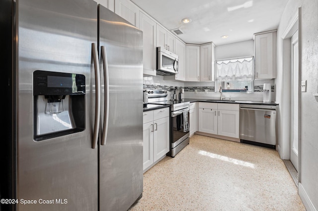 kitchen with backsplash, sink, white cabinets, and stainless steel appliances