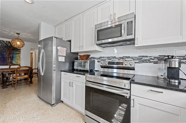 kitchen featuring backsplash, dark stone countertops, white cabinetry, and stainless steel appliances