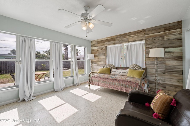 bedroom with ceiling fan and wood walls