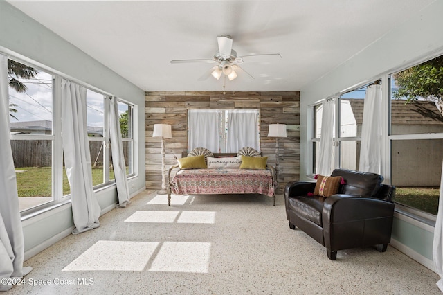 bedroom with multiple windows, wood walls, and ceiling fan