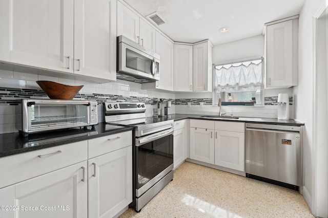 kitchen featuring backsplash, sink, white cabinets, and appliances with stainless steel finishes