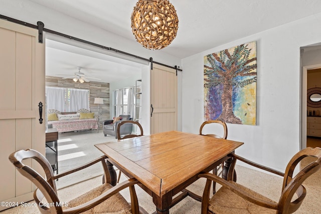 dining area with a barn door and ceiling fan