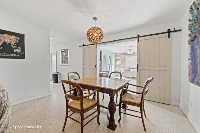 dining area featuring a barn door and ceiling fan