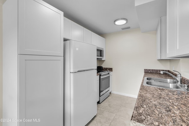 kitchen featuring light tile patterned flooring, appliances with stainless steel finishes, white cabinetry, and sink