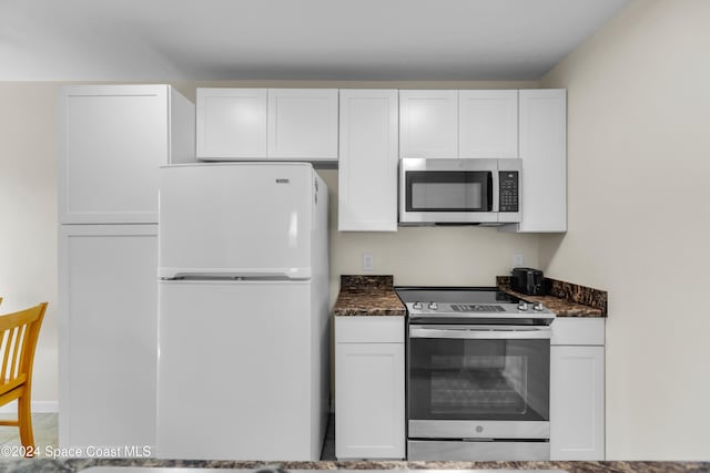 kitchen featuring stainless steel appliances, white cabinetry, and dark stone counters