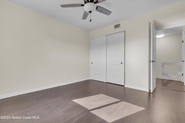 unfurnished bedroom with dark hardwood / wood-style flooring, a closet, and ceiling fan