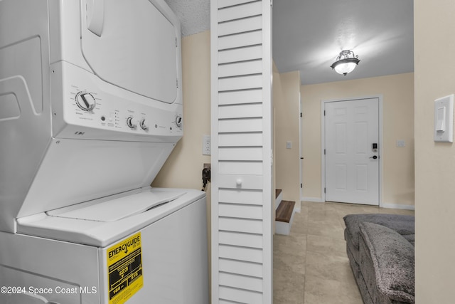 clothes washing area with stacked washing maching and dryer and light tile patterned floors