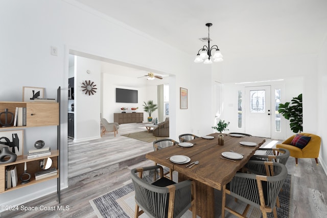 dining space with light hardwood / wood-style flooring and ceiling fan with notable chandelier