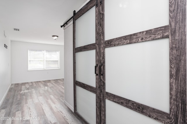 corridor with a barn door and light wood-type flooring