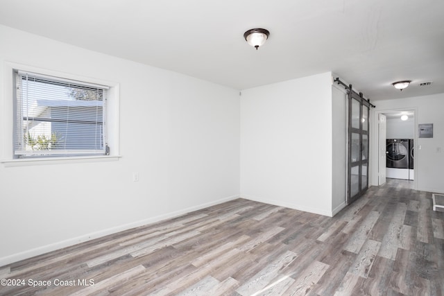 spare room featuring a barn door, hardwood / wood-style floors, and washer and dryer