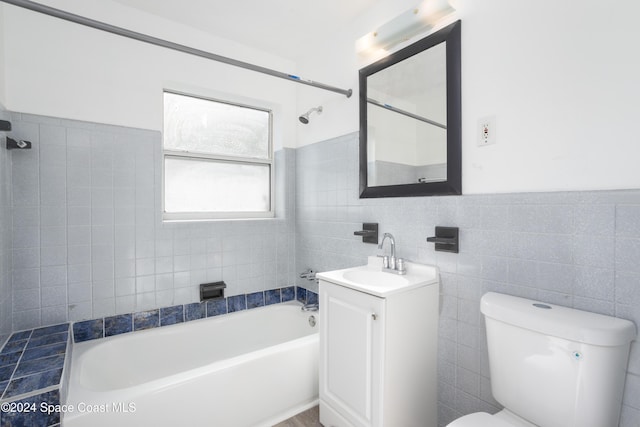 full bathroom with vanity, toilet, and tile walls