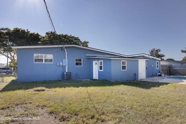 back of property featuring a yard, a fenced in pool, and central AC unit