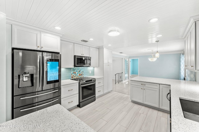 kitchen with pendant lighting, white cabinets, light hardwood / wood-style floors, light stone counters, and stainless steel appliances