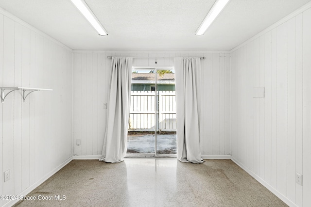 spare room with a textured ceiling and wooden walls