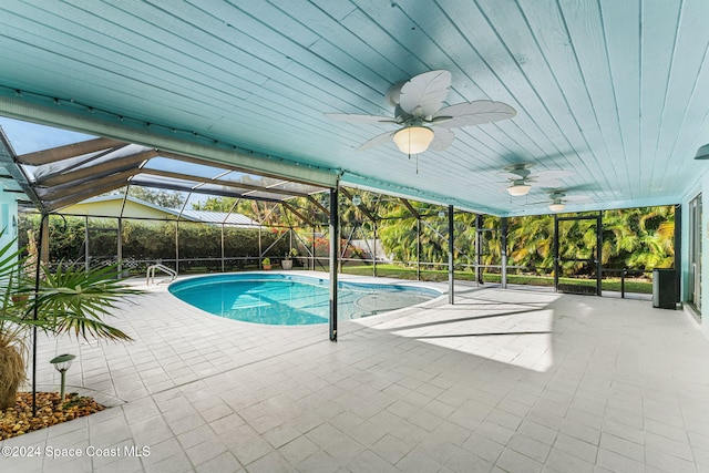 view of pool with glass enclosure, ceiling fan, and a patio area