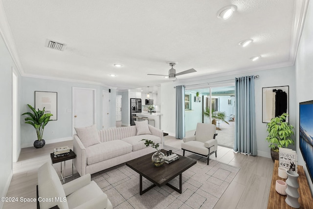 living room featuring ceiling fan, light hardwood / wood-style floors, a textured ceiling, and ornamental molding