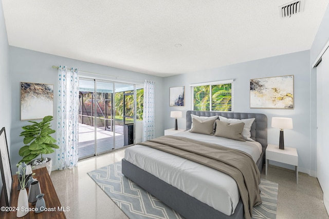 bedroom featuring access to exterior, a textured ceiling, and multiple windows