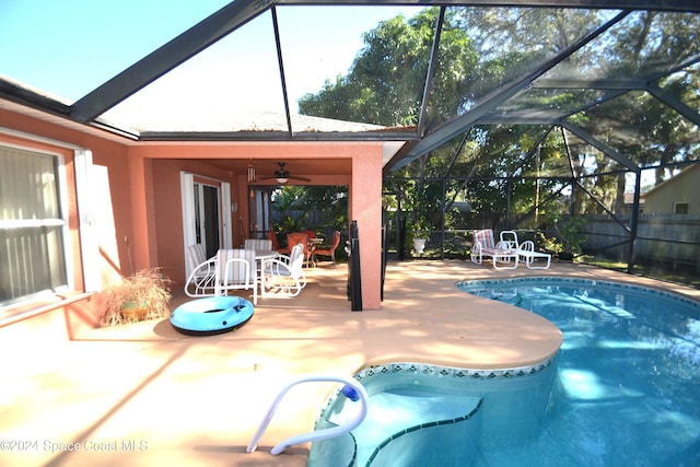 view of swimming pool with a patio, glass enclosure, and ceiling fan