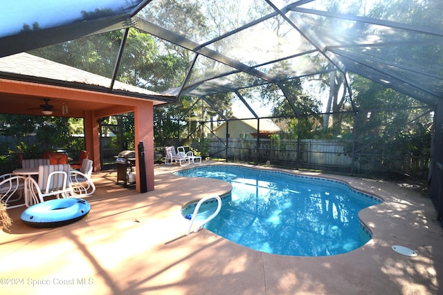 view of swimming pool with grilling area, a patio area, and glass enclosure