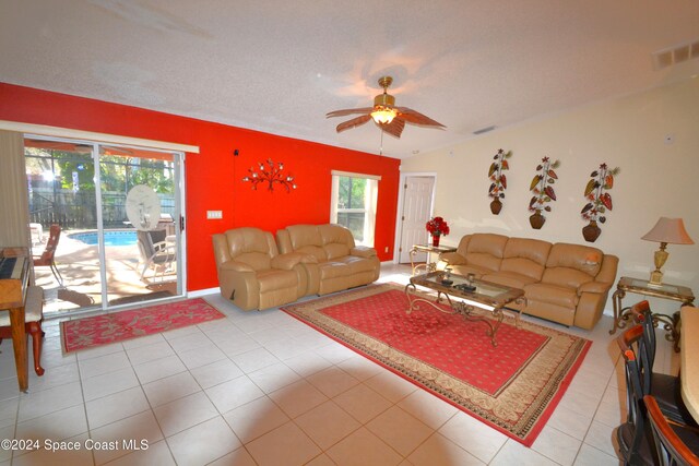 living room with a textured ceiling, ceiling fan, lofted ceiling, and light tile patterned flooring