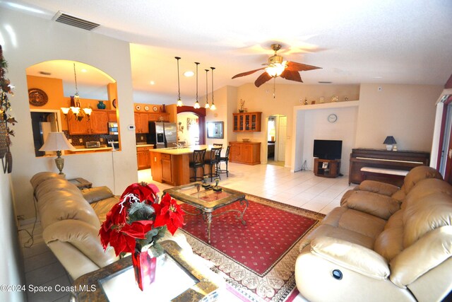 tiled living room featuring ceiling fan with notable chandelier and vaulted ceiling