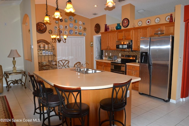 kitchen featuring hanging light fixtures, sink, light tile patterned floors, and stainless steel appliances