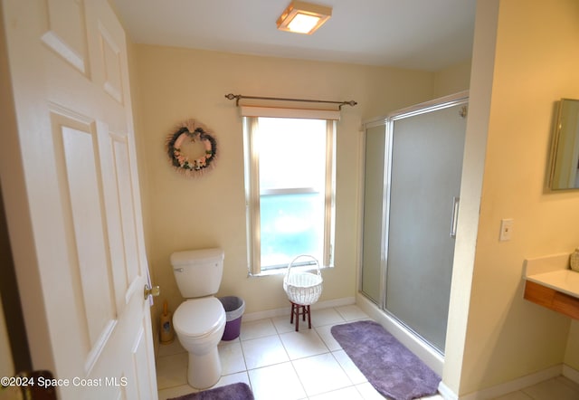 bathroom with tile patterned flooring, toilet, and a shower with door