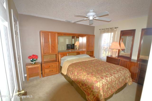 bedroom with a textured ceiling, ceiling fan, and light carpet