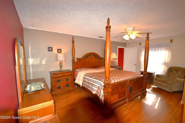 bedroom with ceiling fan, wood-type flooring, and a textured ceiling