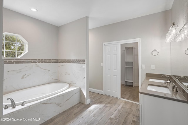 bathroom featuring hardwood / wood-style flooring, vanity, tile walls, and tiled tub