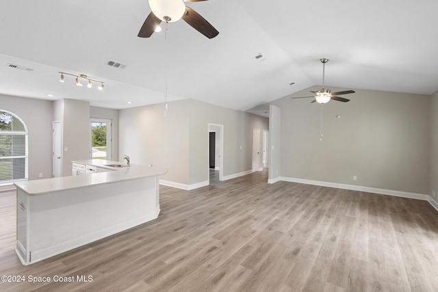 kitchen with vaulted ceiling, light hardwood / wood-style flooring, a center island with sink, and sink