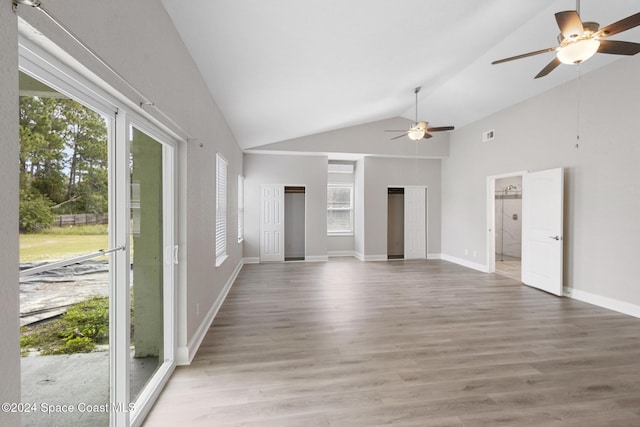 unfurnished living room featuring plenty of natural light, ceiling fan, wood-type flooring, and high vaulted ceiling