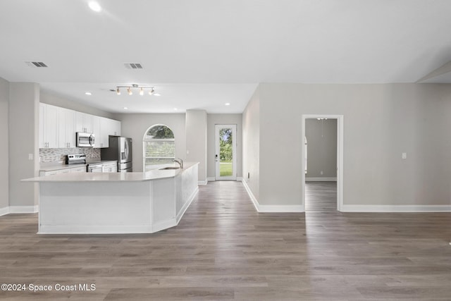 kitchen featuring white cabinets, sink, an island with sink, appliances with stainless steel finishes, and wood-type flooring