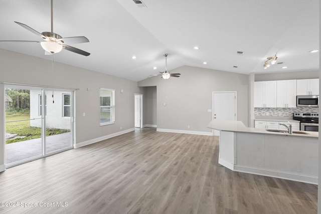 kitchen featuring decorative backsplash, appliances with stainless steel finishes, vaulted ceiling, light hardwood / wood-style flooring, and white cabinetry