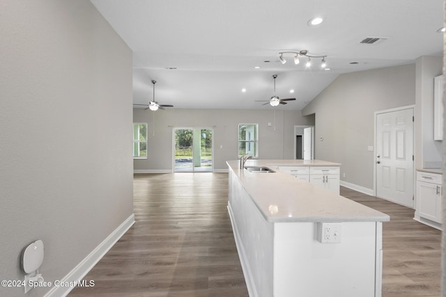 kitchen with white cabinets, a center island with sink, vaulted ceiling, and hardwood / wood-style flooring