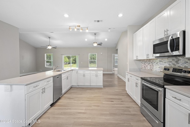 kitchen featuring sink, decorative backsplash, light wood-type flooring, white cabinetry, and stainless steel appliances