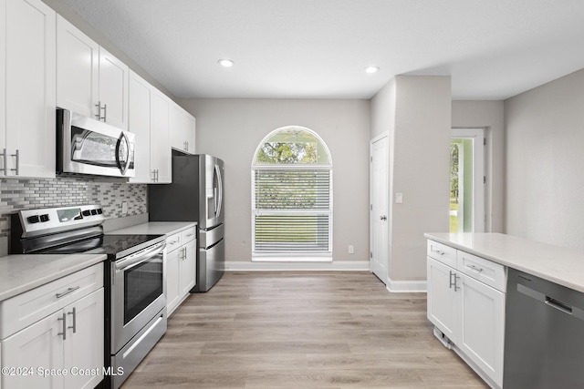 kitchen featuring tasteful backsplash, white cabinetry, stainless steel appliances, and light hardwood / wood-style floors