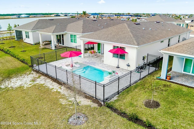 view of swimming pool with a patio area, a yard, and a water view