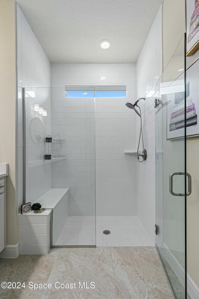 bathroom with vanity, a textured ceiling, walk in shower, and tile patterned flooring