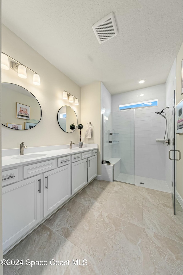 bathroom with vanity, a shower with door, and a textured ceiling