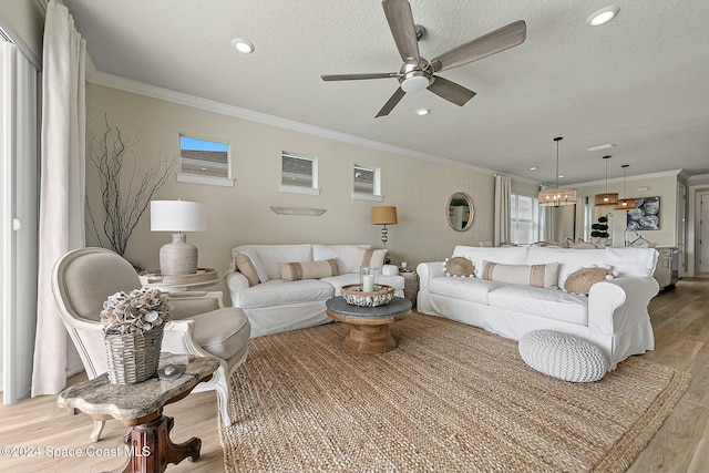 living room featuring ceiling fan, light hardwood / wood-style flooring, a textured ceiling, and ornamental molding