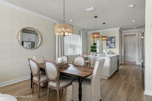 dining room with light wood-type flooring, a textured ceiling, and ornamental molding